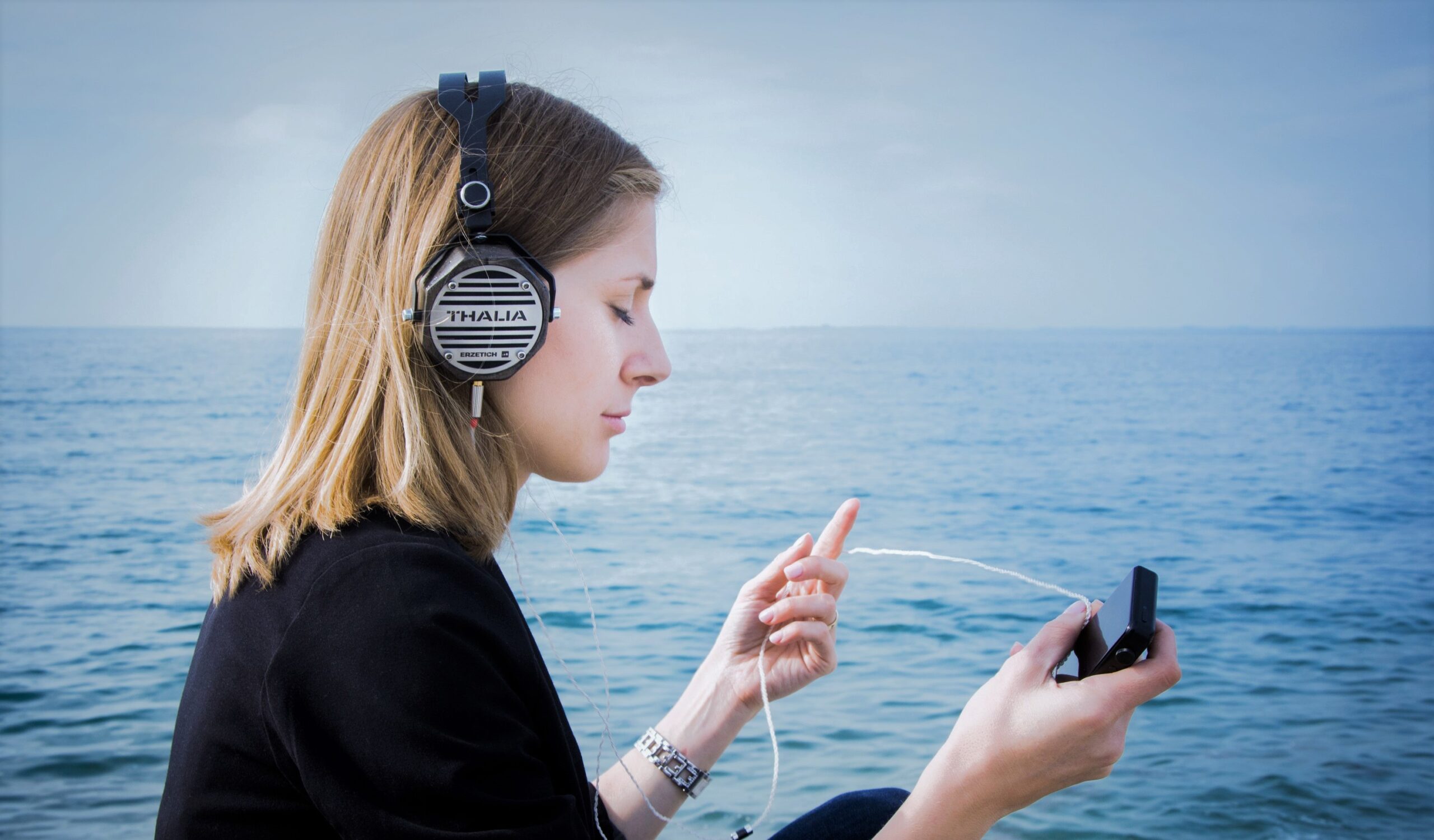 A woman listens to her music player at the ocean