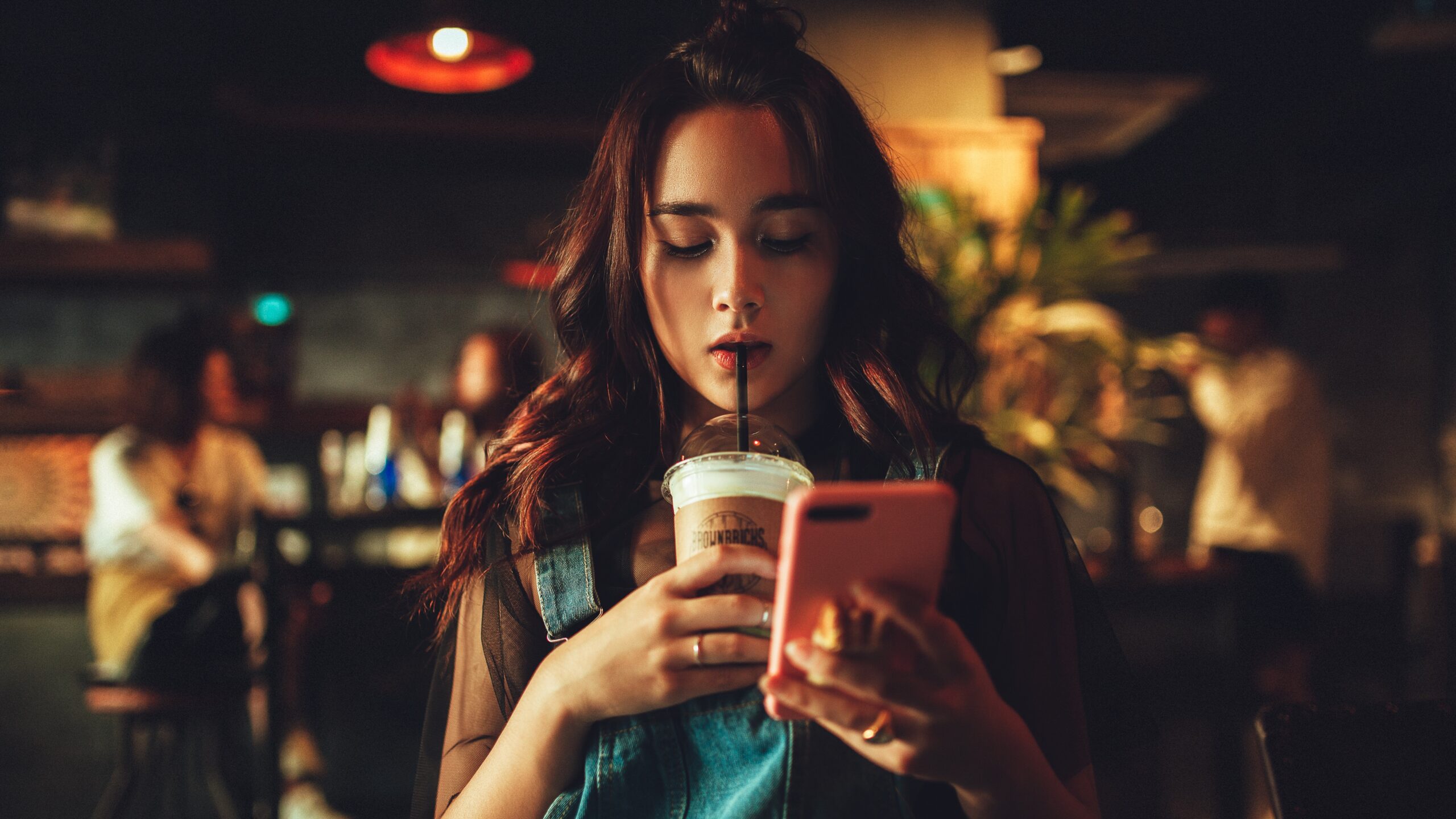 Woman drinking coffee and looking at her phone