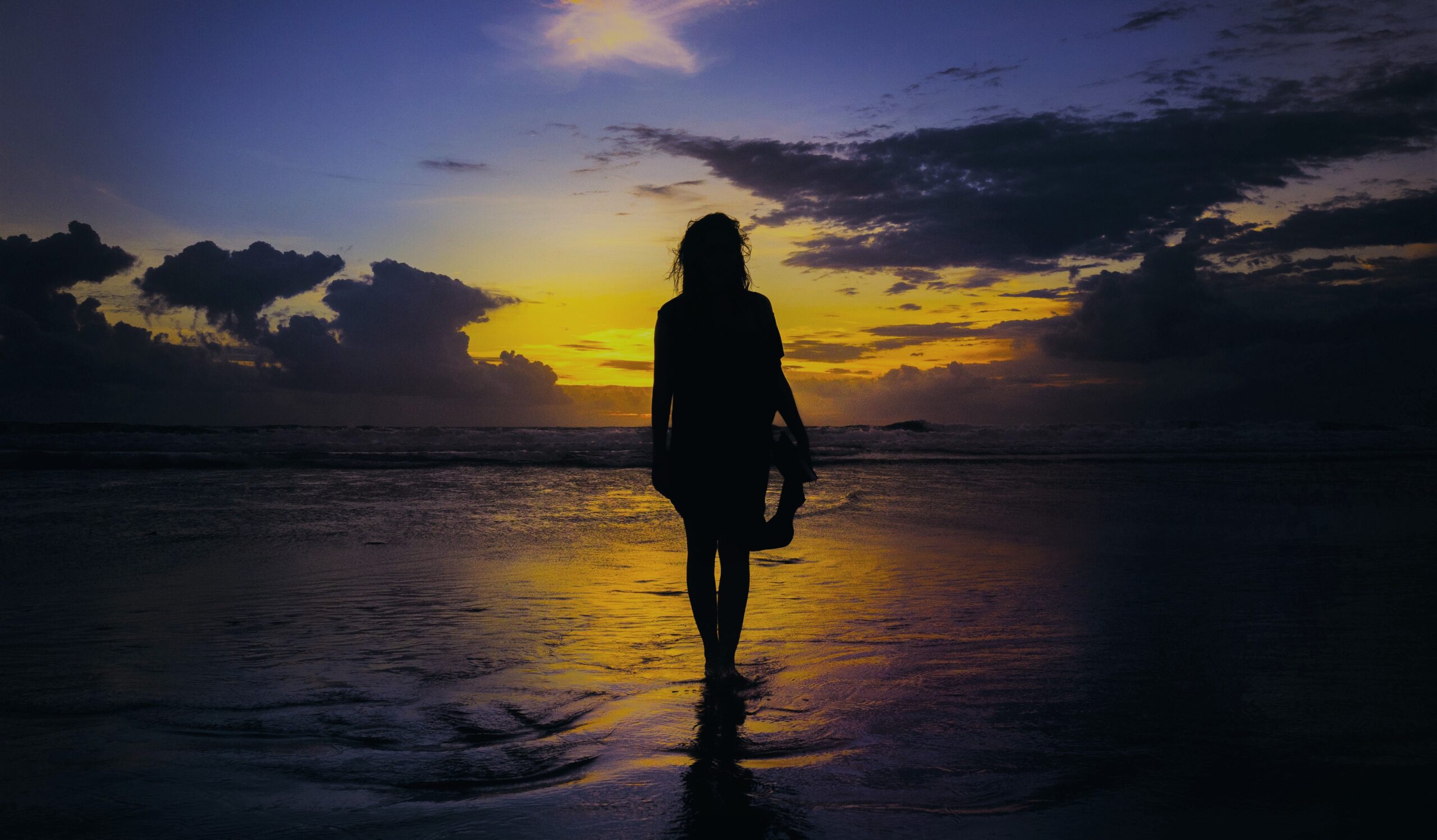 A woman stands in the water on a beach