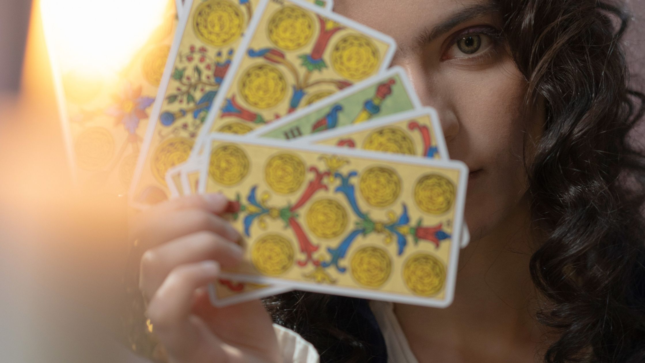 Woman holding tarot cards in front of her face