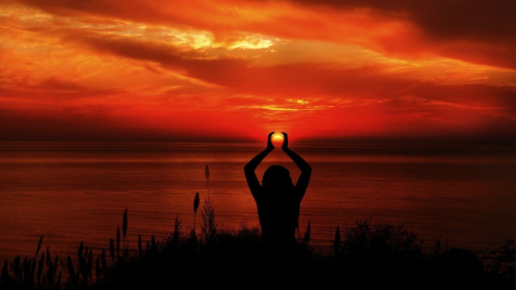 Woman meditating at the waterfront at sunset