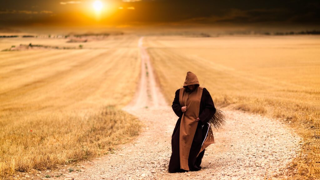 Monk walking on a country road away from the sun