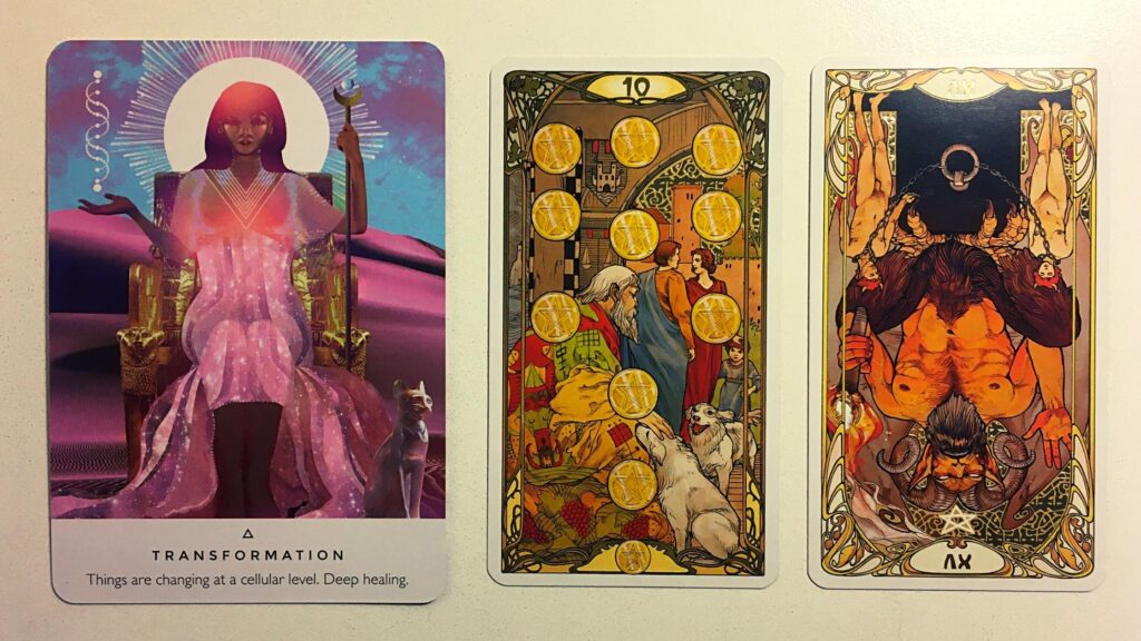 Transformation card from the Work Your Light oracle deck; the Ten of Pentacles and the Devil, Reversed from the Golden Art Nouveau Tarot deck