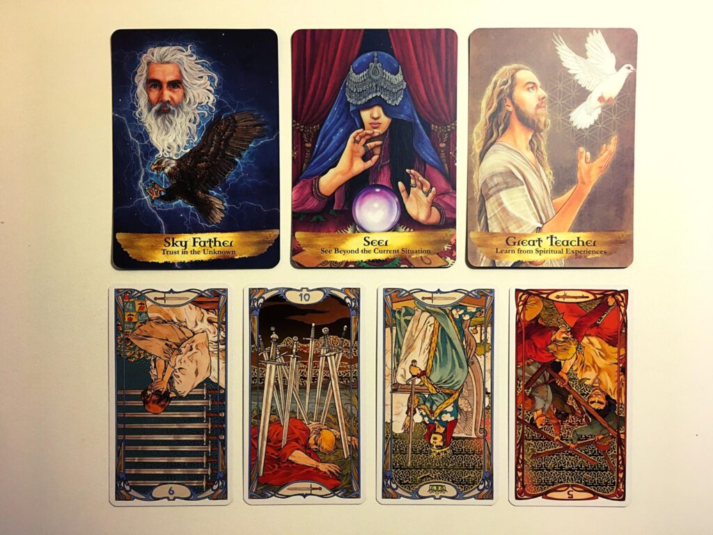 Sky Father, Seer, and Great Teacher cards from the Angels and Ancestors oracle deck; the Nine of Swords reversed, the Ten of Swords, the Queen of Swords revered, and the Five of Wands reversed from the Golden Art Nouveau tarot deck