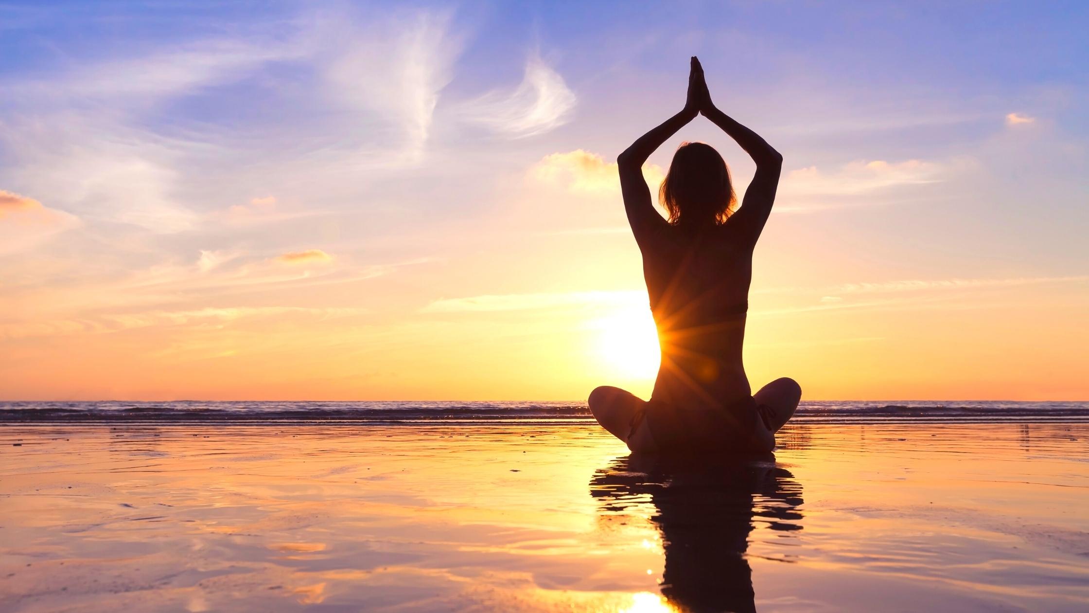 A woman meditating by the ocean